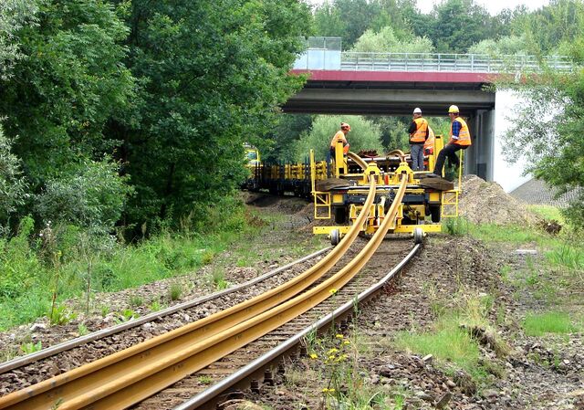Rozładunek długiej szyny z wagonów.